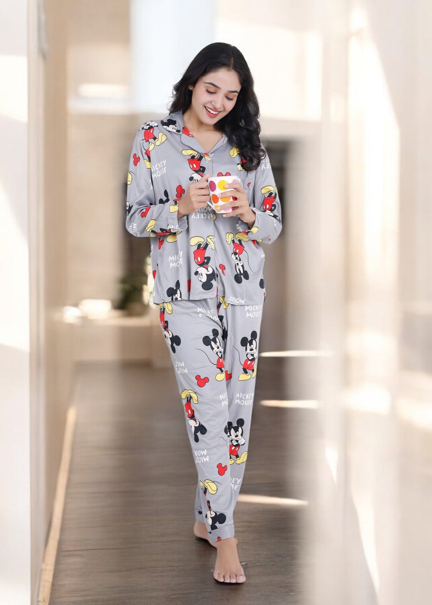 Woman in grey jersey cotton pyjama set with all-over Mickey Mouse print, cozy cartoon loungewear by WakeUp Chicq.