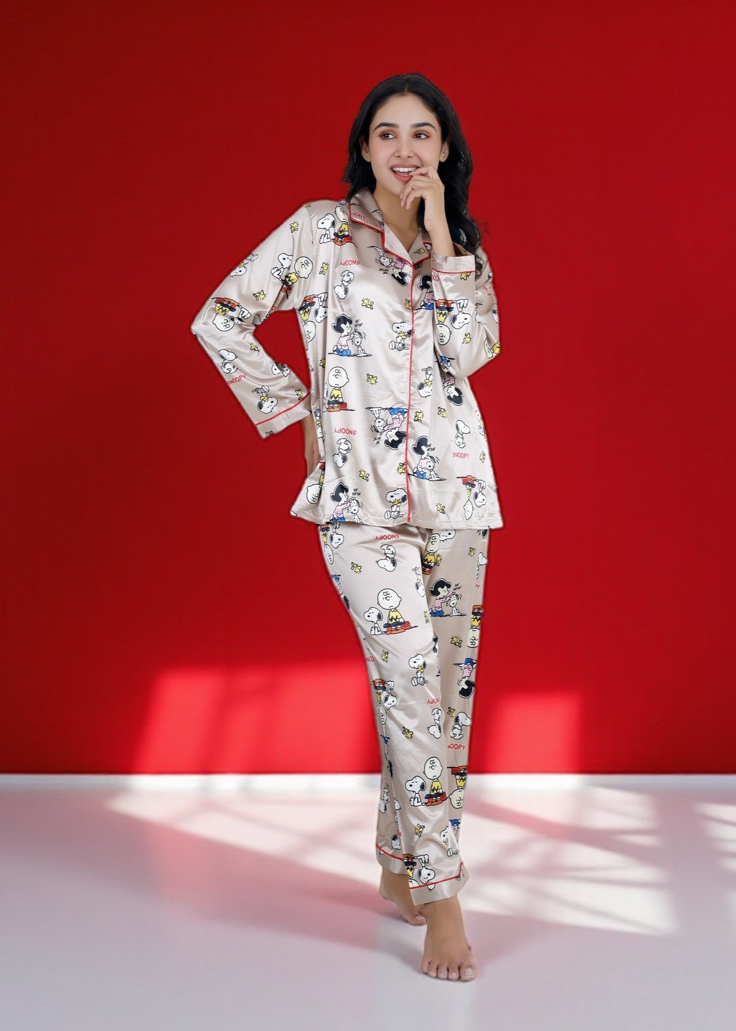 Woman wearing a beige satin Snoopy pyjama set with full sleeves and Peanuts print