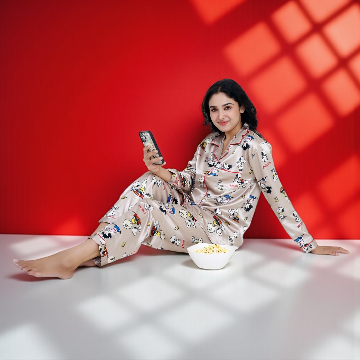 Woman wearing a beige satin Snoopy pyjama set with full sleeves and Peanuts print