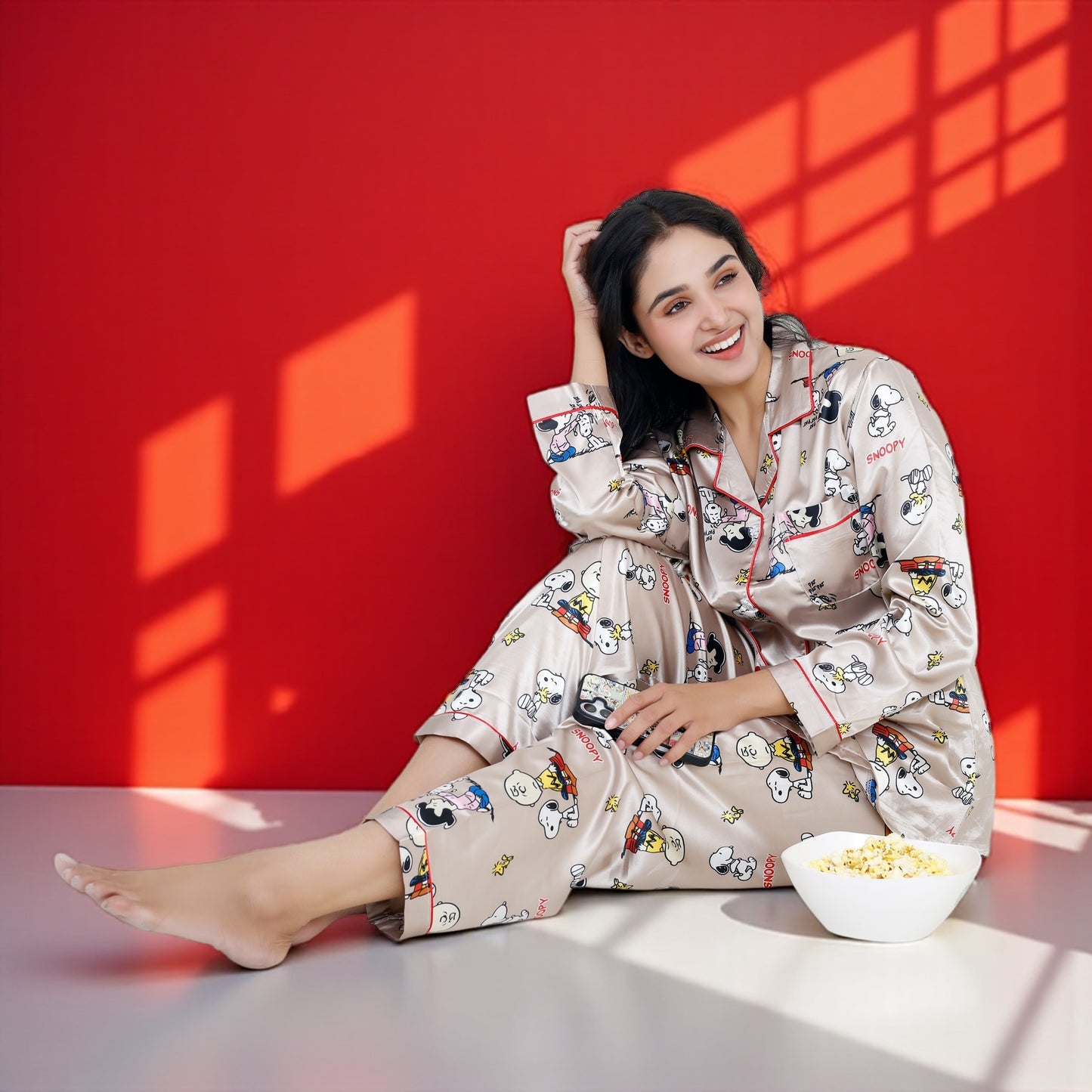 Woman wearing a beige satin Snoopy pyjama set with full sleeves and Peanuts print