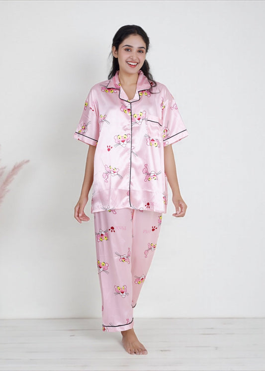 Woman wearing baby pink satin pyjama set with Pink Panther cartoon print and black piping, luxe loungewear by WakeUp Chicq.