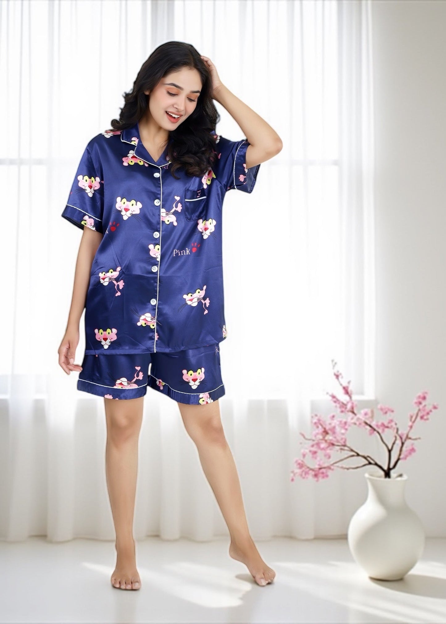 Woman wearing royal blue satin shorts set with vibrant Pink Panther cartoon print, short-sleeve collared shirt and matching shorts, by WakeUp Chicq.