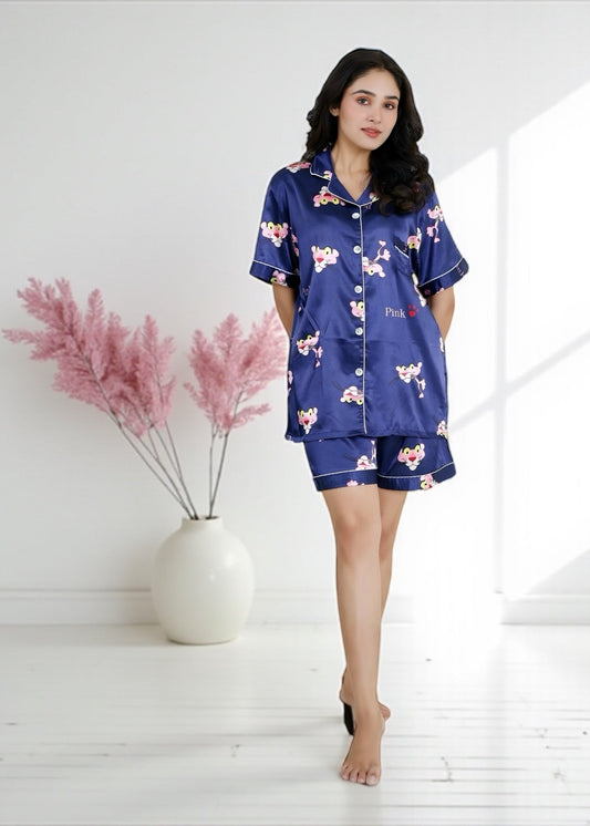 Woman wearing royal blue satin shorts set with vibrant Pink Panther cartoon print, short-sleeve collared shirt and matching shorts, by WakeUp Chicq.