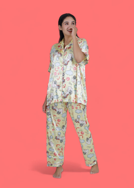 Woman wearing creamy yellow satin unicorn pyjama set with cloud motifs, full-length luxury loungewear by WakeUp Chicq.