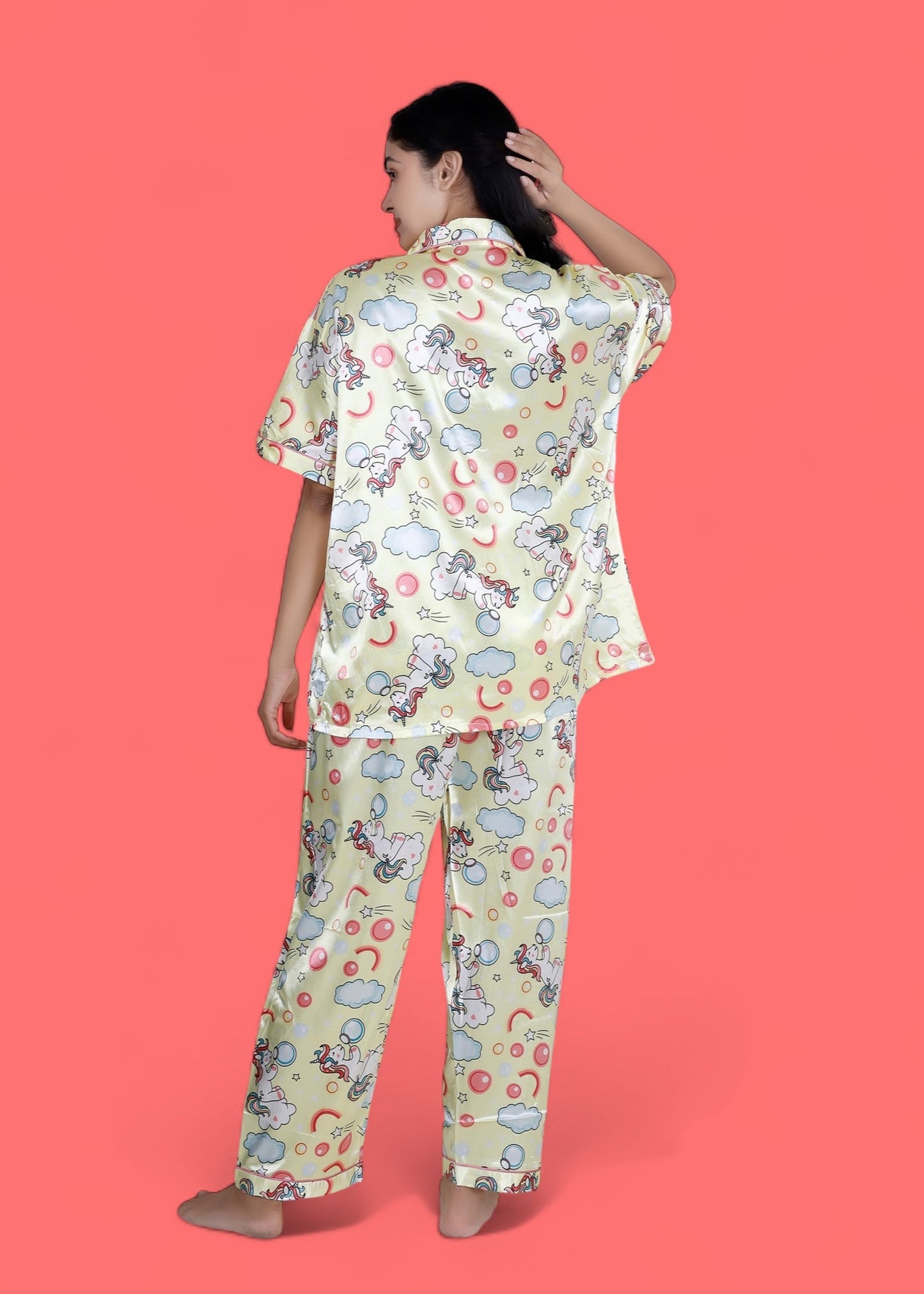 Woman wearing creamy yellow satin unicorn pyjama set with cloud motifs, full-length luxury loungewear by WakeUp Chicq.