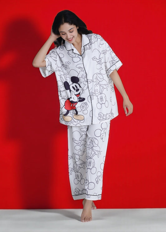 Woman wearing white crepe pyjama set with oversized Mickey Mouse cartoon print, relaxed Disney loungewear by WakeUp Chicq.