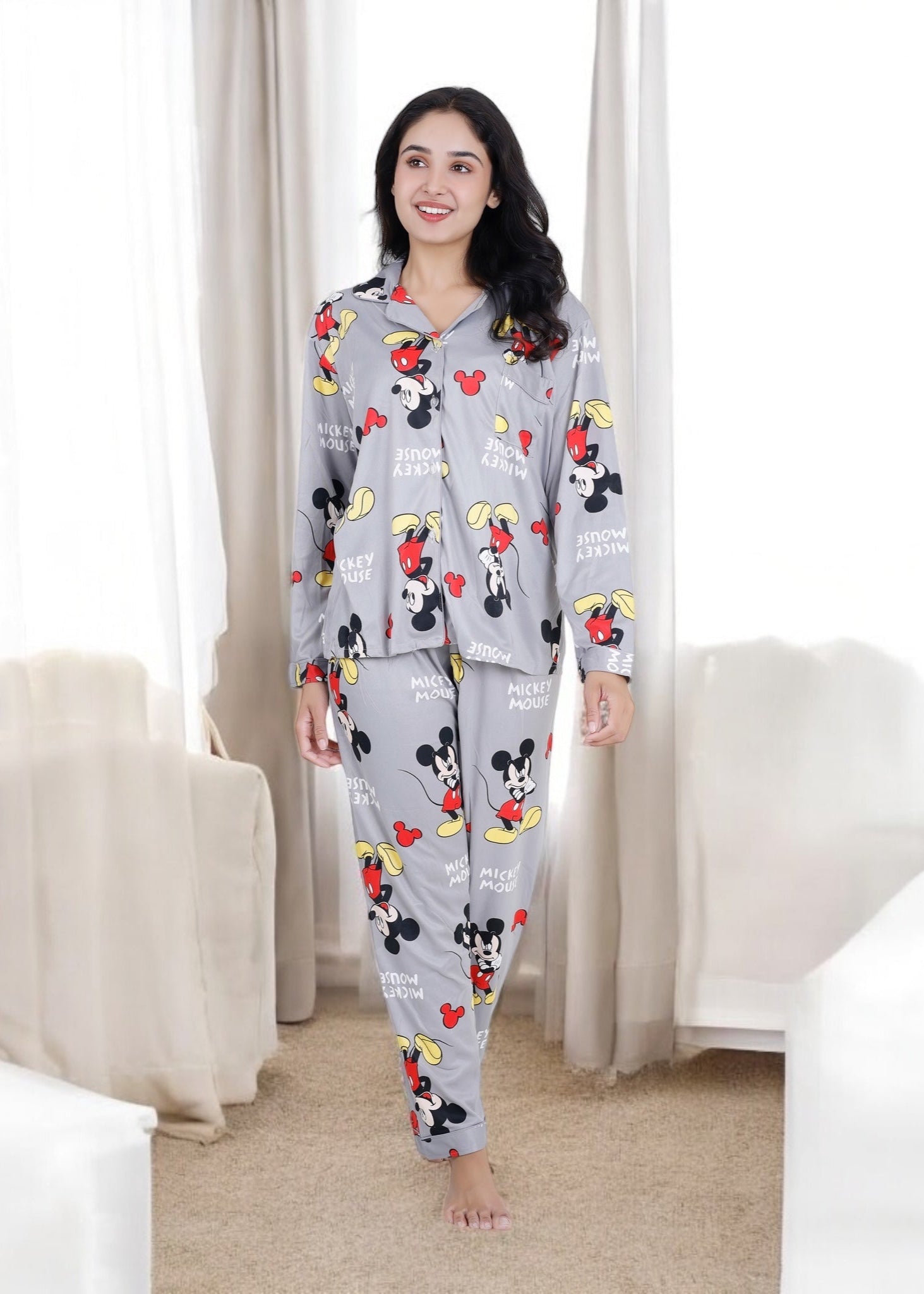 Woman in grey jersey cotton pyjama set with all-over Mickey Mouse print, cozy cartoon loungewear by WakeUp Chicq.

