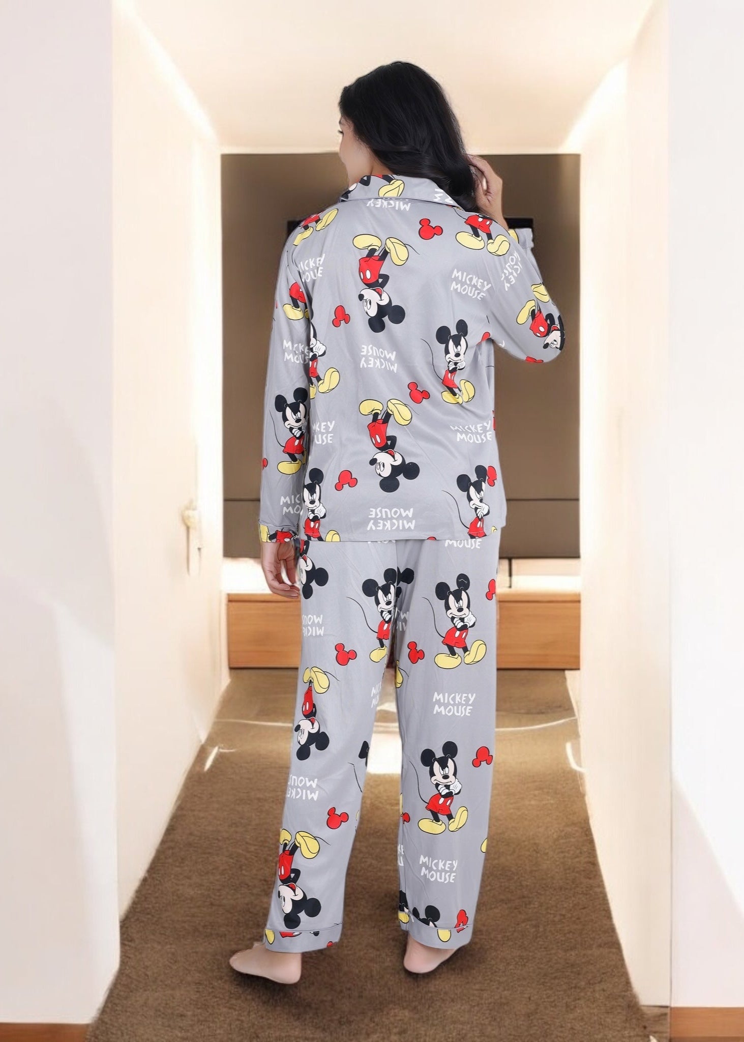 Woman in grey jersey cotton pyjama set with all-over Mickey Mouse print, cozy cartoon loungewear by WakeUp Chicq.

