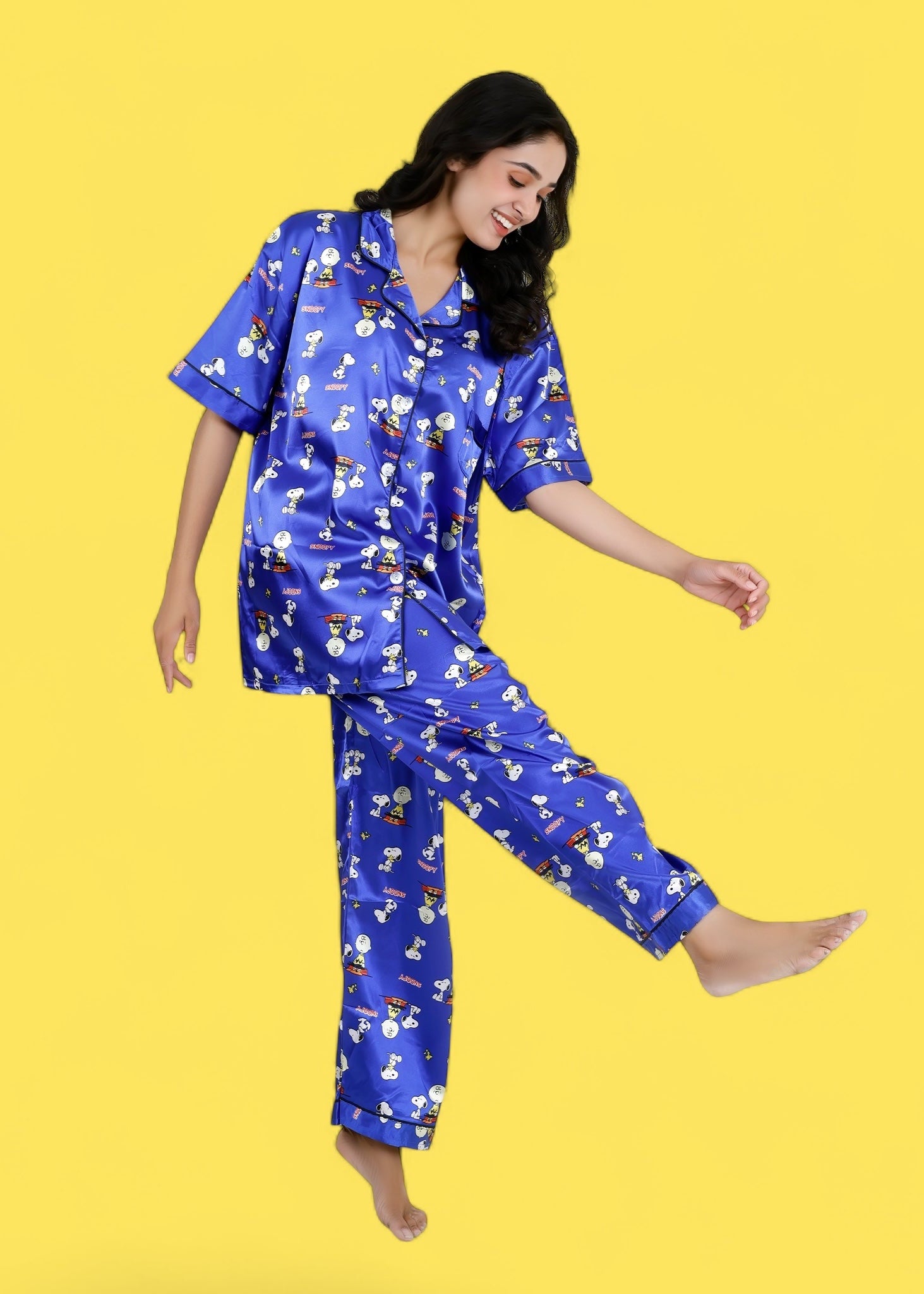 Woman wearing royal blue satin Snoopy print pyjama set with white piping, long pants, and short-sleeve shirt, nightwear by WakeUp Chicq.

