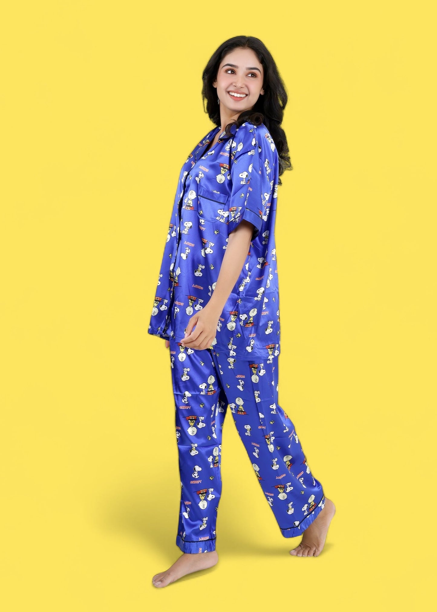 Woman wearing royal blue satin Snoopy print pyjama set with white piping, long pants, and short-sleeve shirt, nightwear by WakeUp Chicq.

