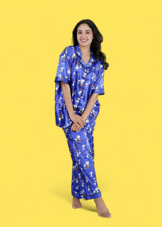 Woman wearing royal blue satin Snoopy print pyjama set with white piping, long pants, and short-sleeve shirt, nightwear by WakeUp Chicq.

