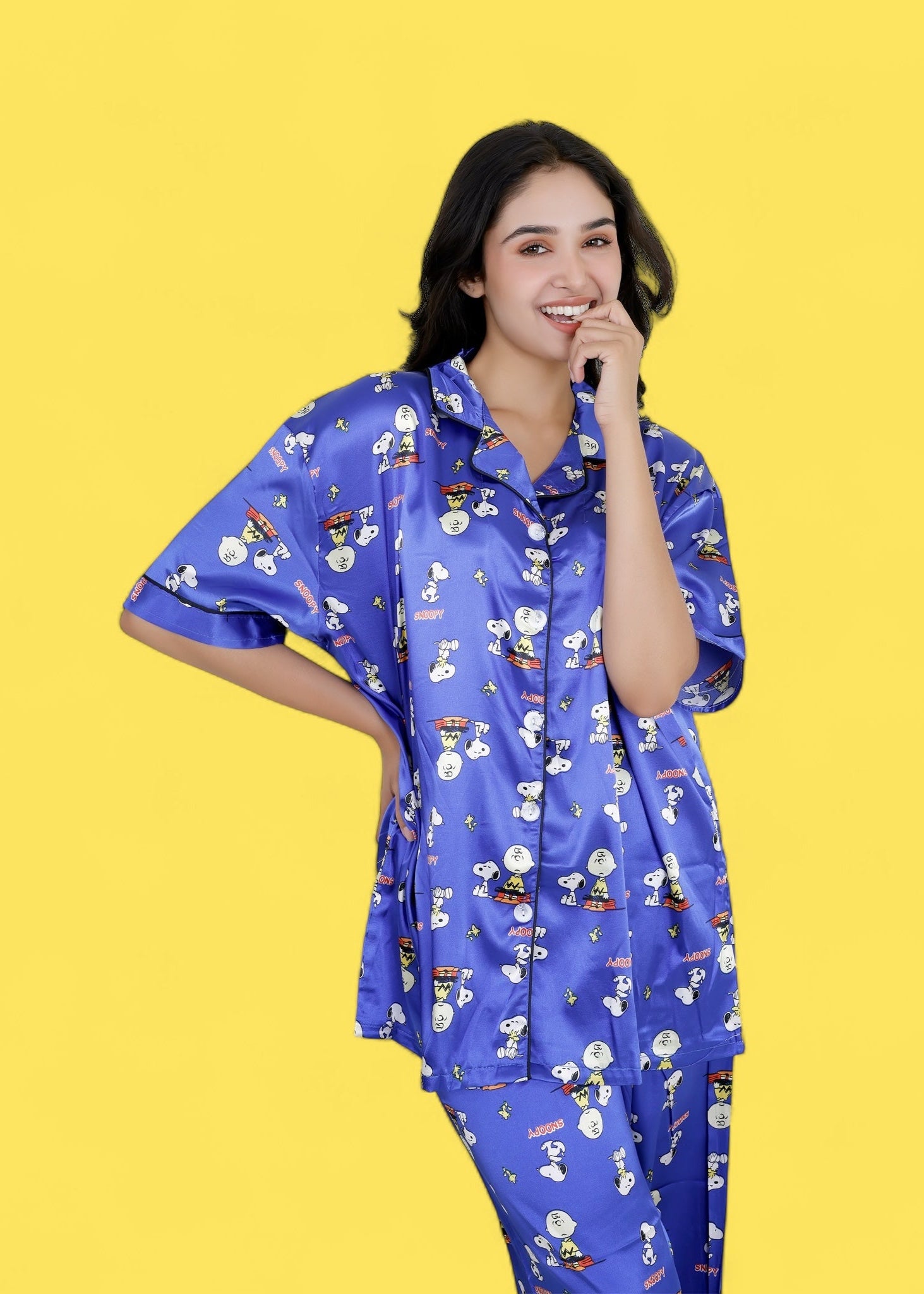 Woman wearing royal blue satin Snoopy print pyjama set with white piping, long pants, and short-sleeve shirt, nightwear by WakeUp Chicq.

