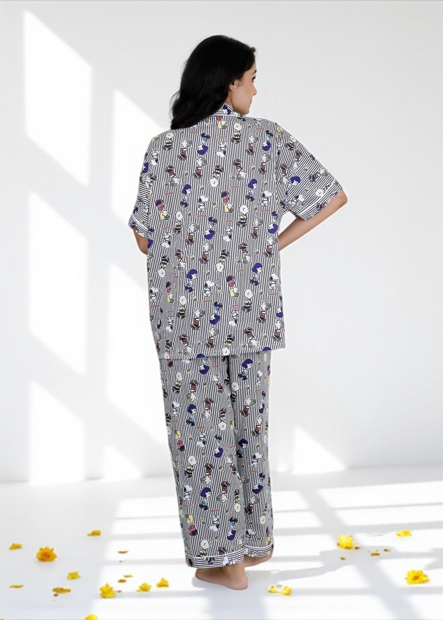 Woman wearing Snoopy cartoon black-and-white striped crepe pyjama set with relaxed fit, stylish nightwear by WakeUp Chicq.