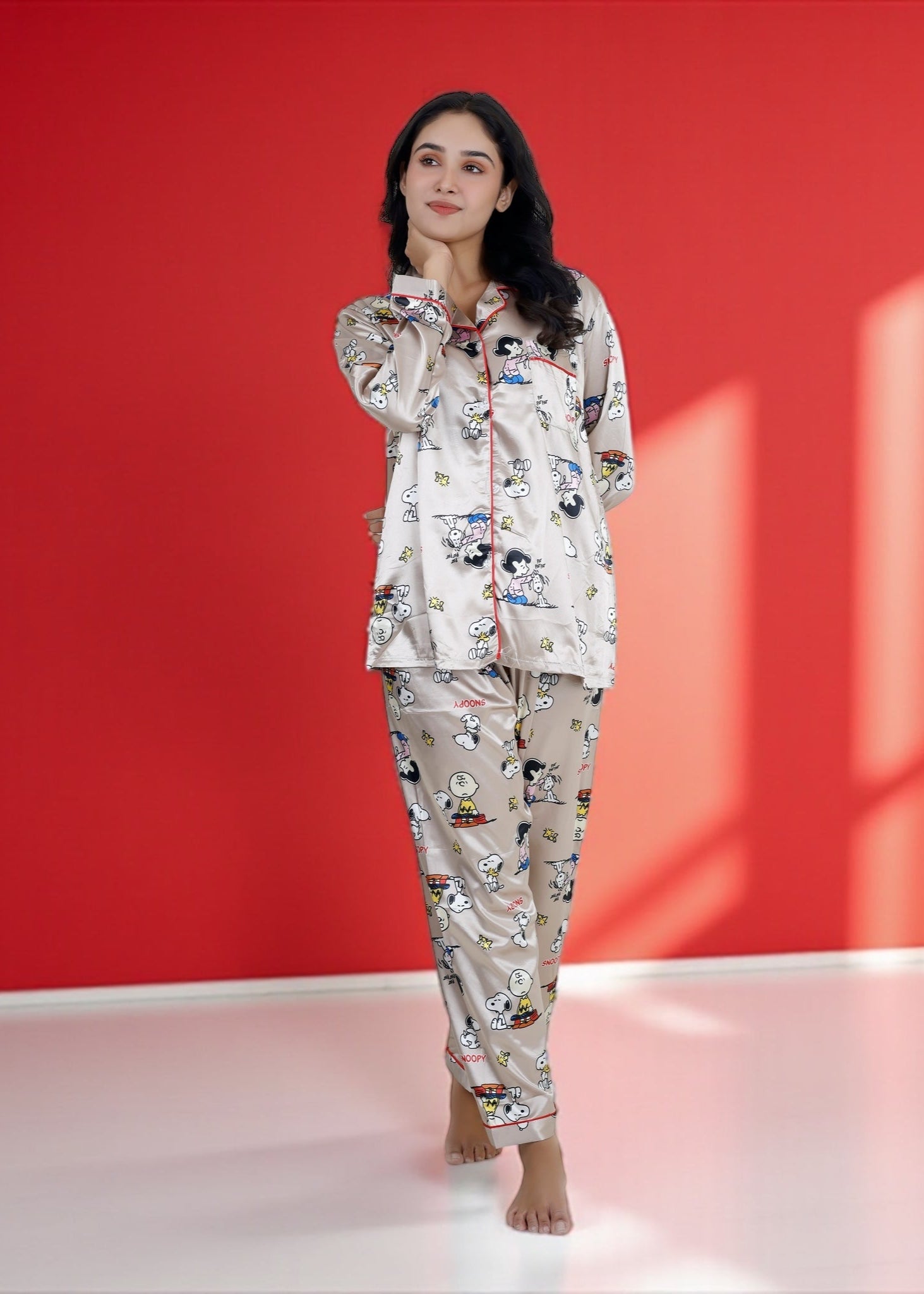 Woman wearing a beige satin Snoopy pyjama set with full sleeves and Peanuts print

