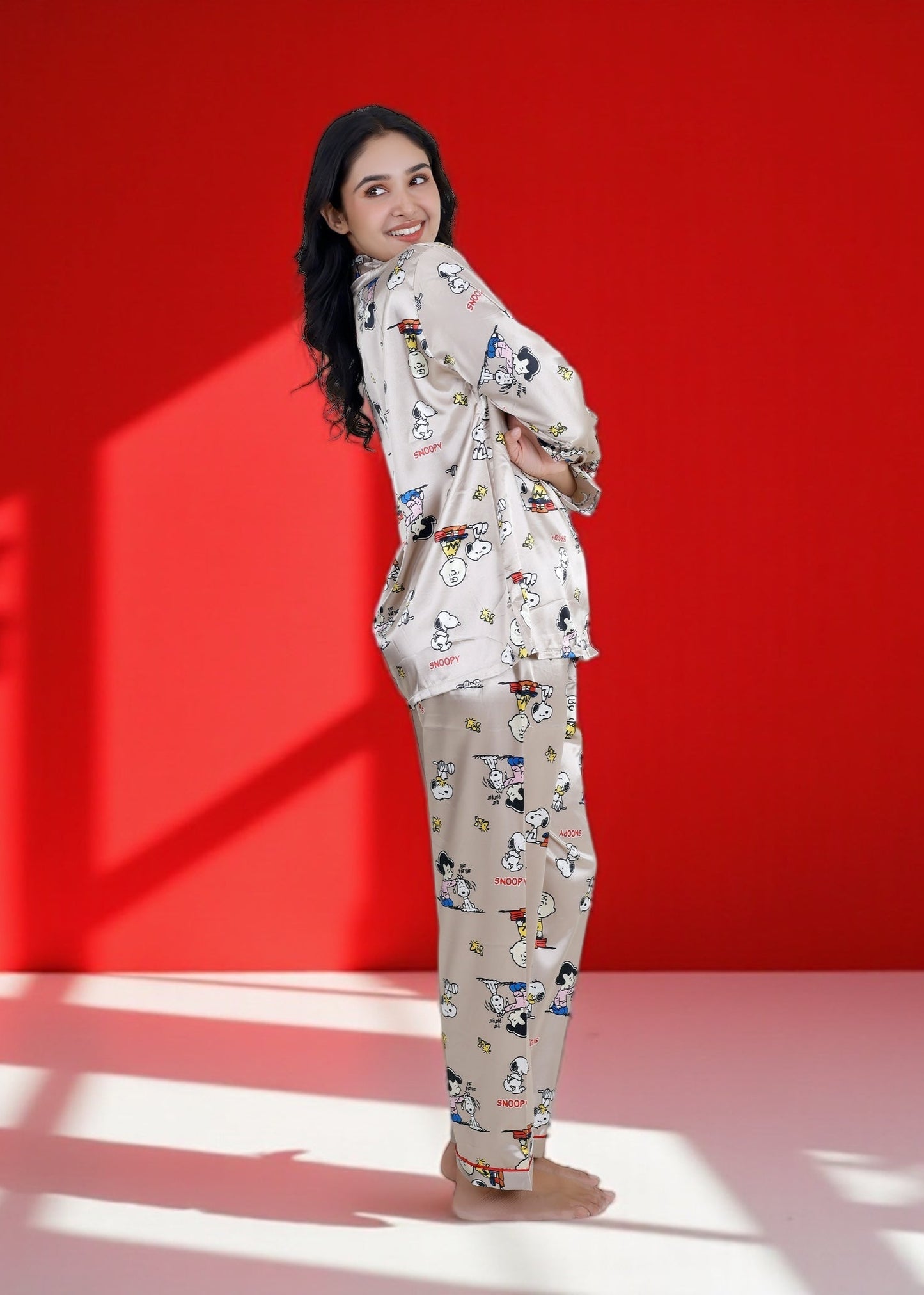 Woman wearing a beige satin Snoopy pyjama set with full sleeves and Peanuts print

