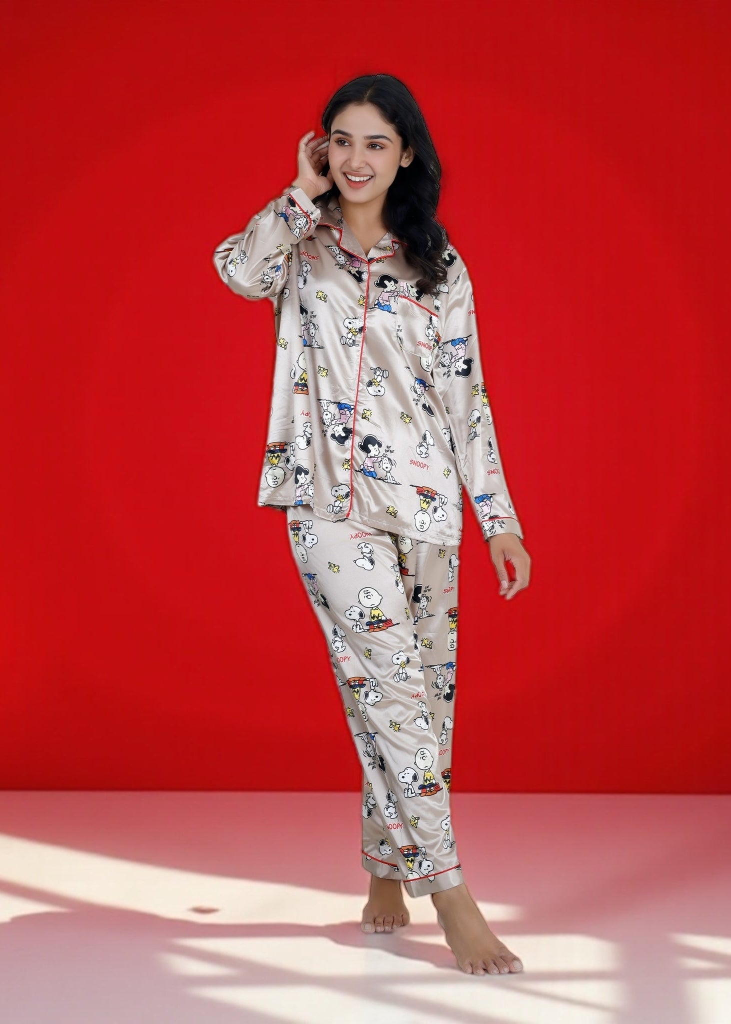 Woman wearing a beige satin Snoopy pyjama set with full sleeves and Peanuts print

