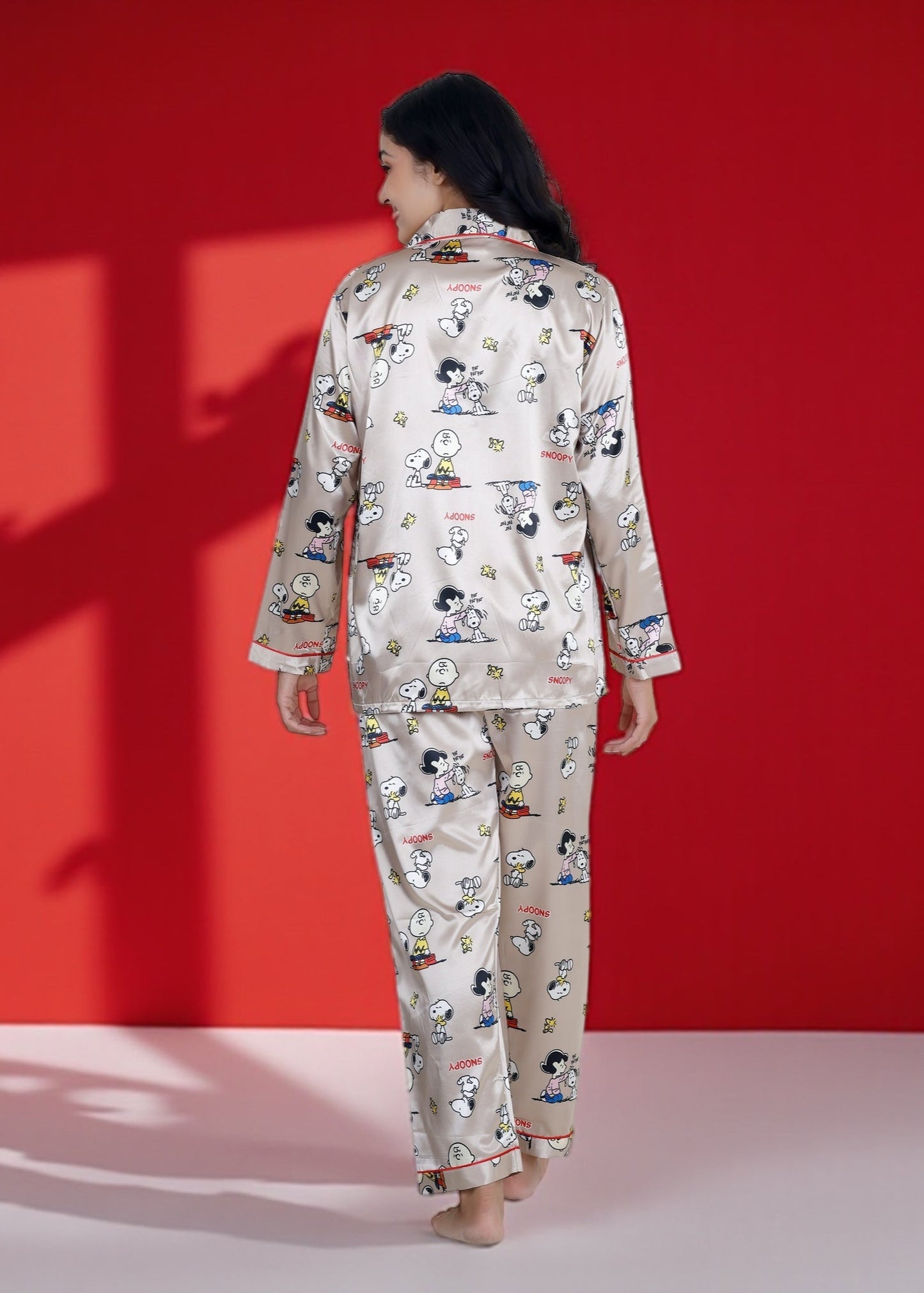 Woman wearing a beige satin Snoopy pyjama set with full sleeves and Peanuts print

