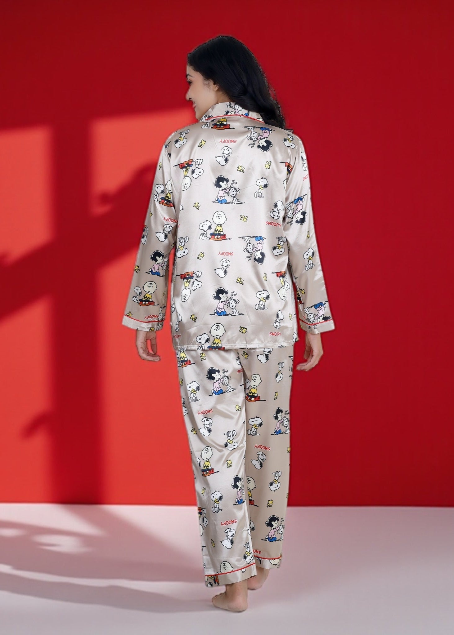 Woman wearing a beige satin Snoopy pyjama set with full sleeves and Peanuts print

