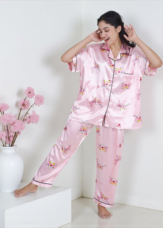 Woman wearing baby pink satin pyjama set with Pink Panther cartoon print and black piping, luxe loungewear by WakeUp Chicq.

