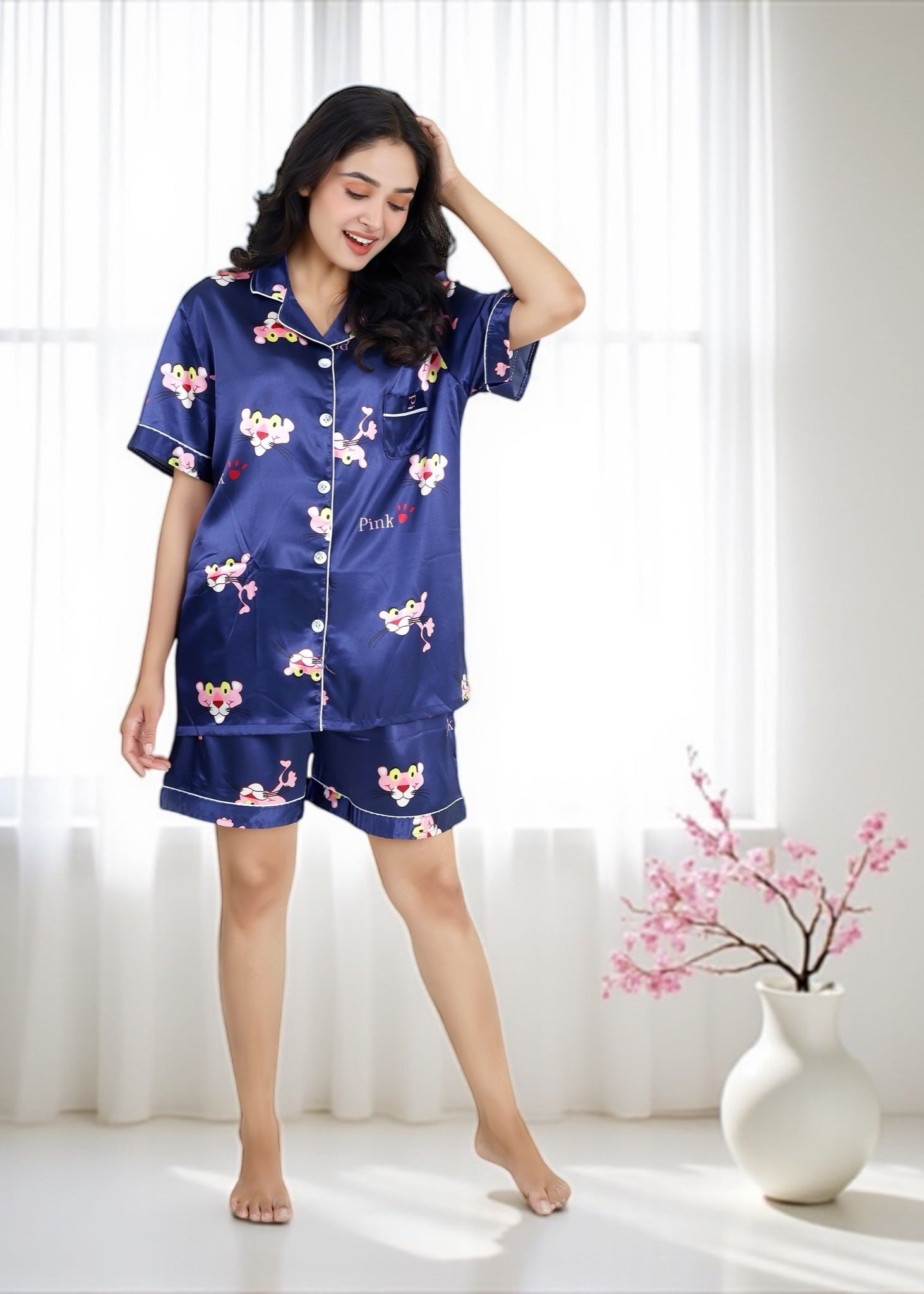 Woman wearing royal blue satin shorts set with vibrant Pink Panther cartoon print, short-sleeve collared shirt and matching shorts, by WakeUp Chicq.

