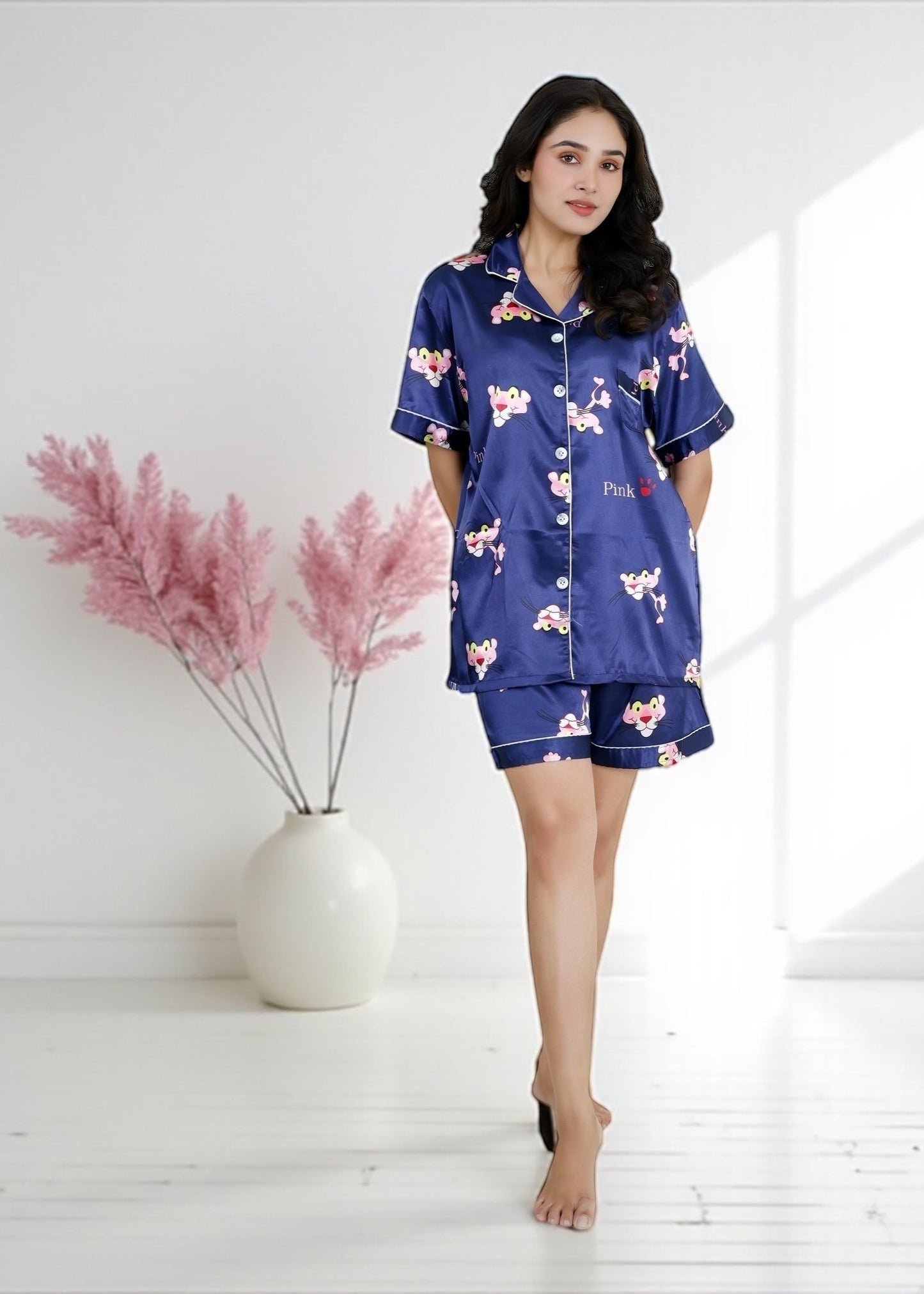 Woman wearing royal blue satin shorts set with vibrant Pink Panther cartoon print, short-sleeve collared shirt and matching shorts, by WakeUp Chicq.

