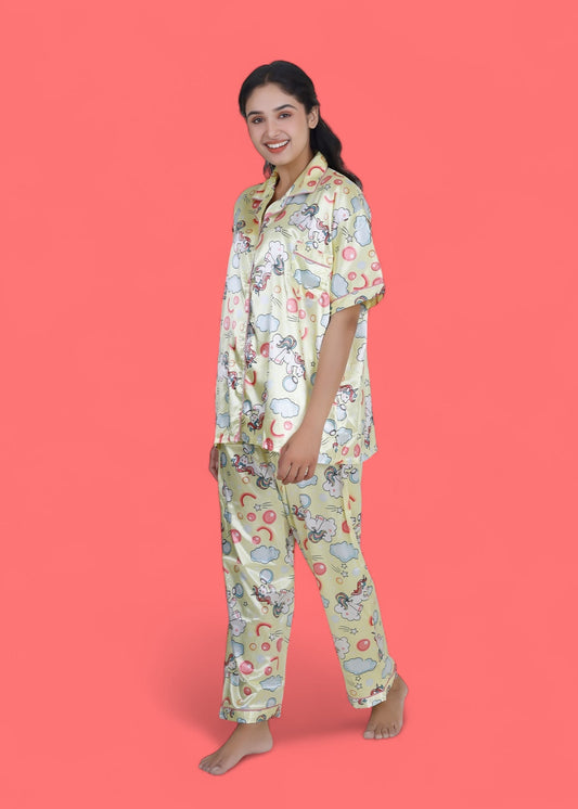Woman wearing creamy yellow satin unicorn pyjama set with cloud motifs, full-length luxury loungewear by WakeUp Chicq.