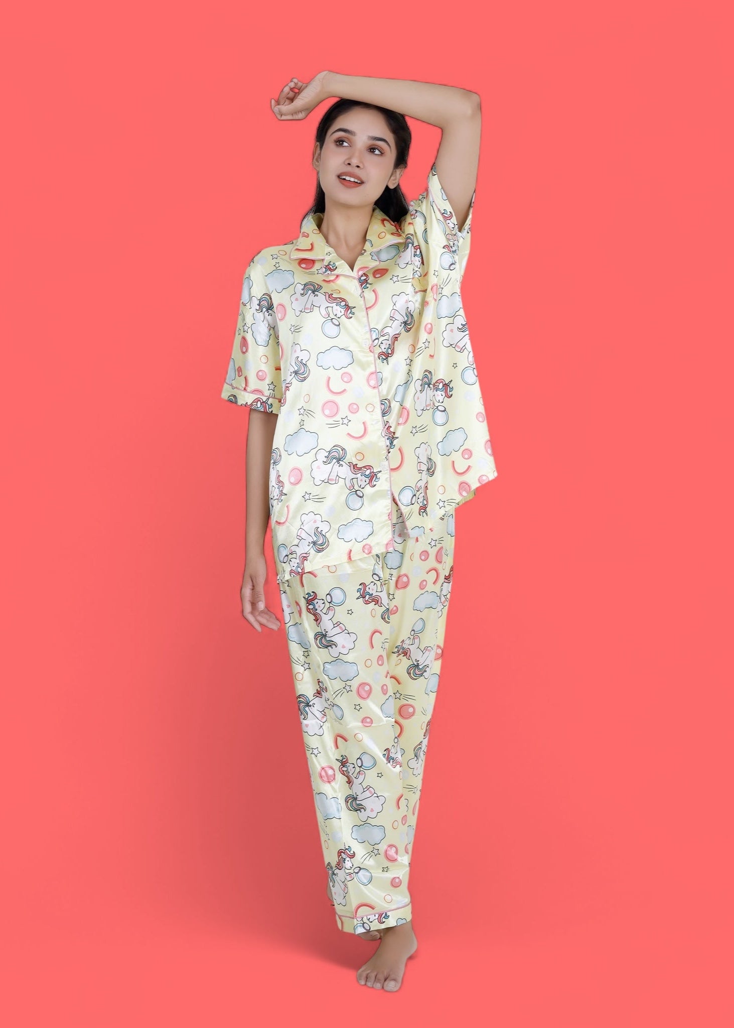 Woman wearing creamy yellow satin unicorn pyjama set with cloud motifs, full-length luxury loungewear by WakeUp Chicq.