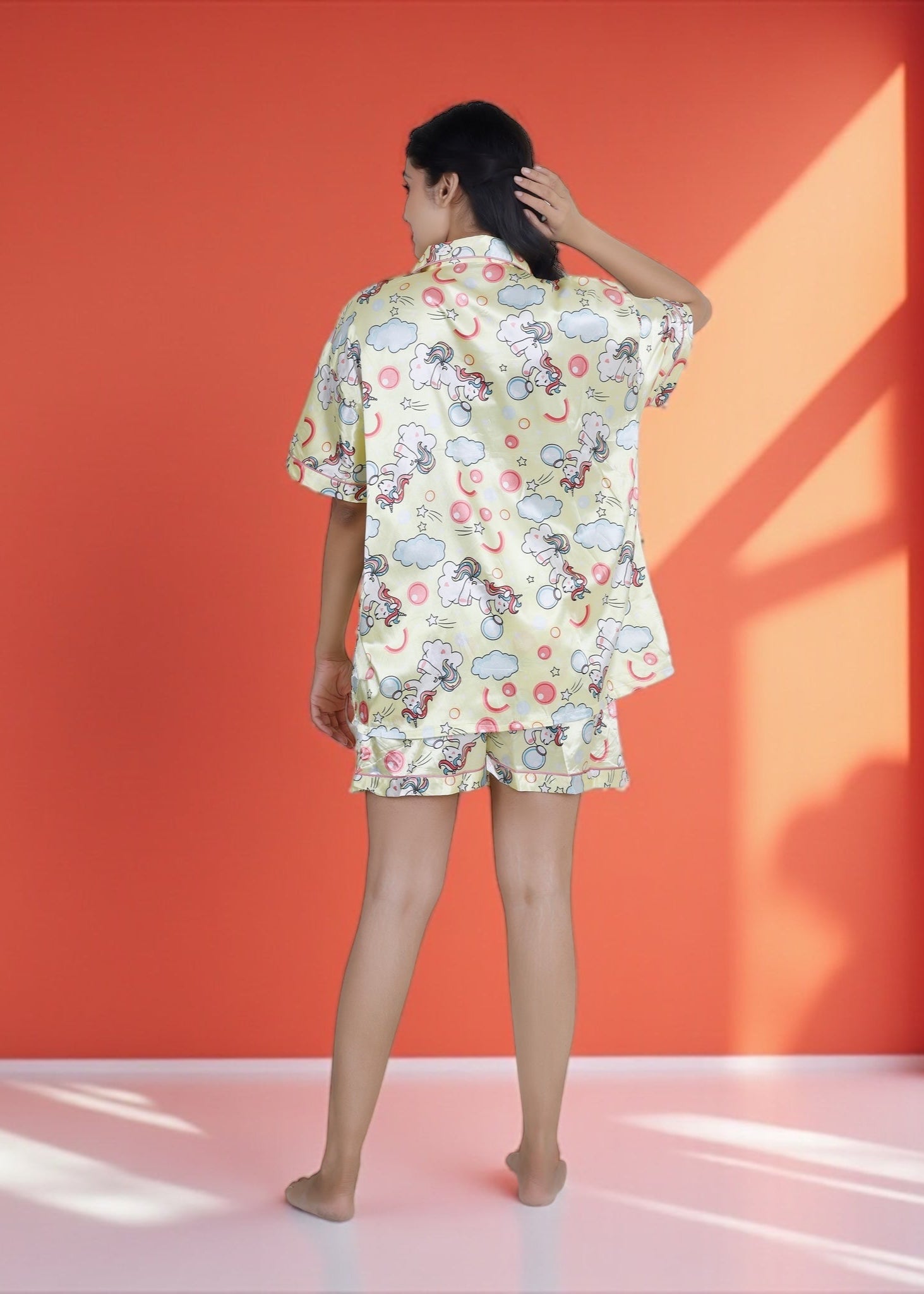 Woman wearing pastel yellow satin unicorn shorts set with black piping, whimsical luxury loungewear by WakeUp Chicq.

