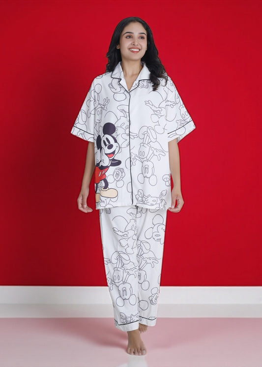 Woman wearing white crepe pyjama set with oversized Mickey Mouse cartoon print, relaxed Disney loungewear by WakeUp Chicq.