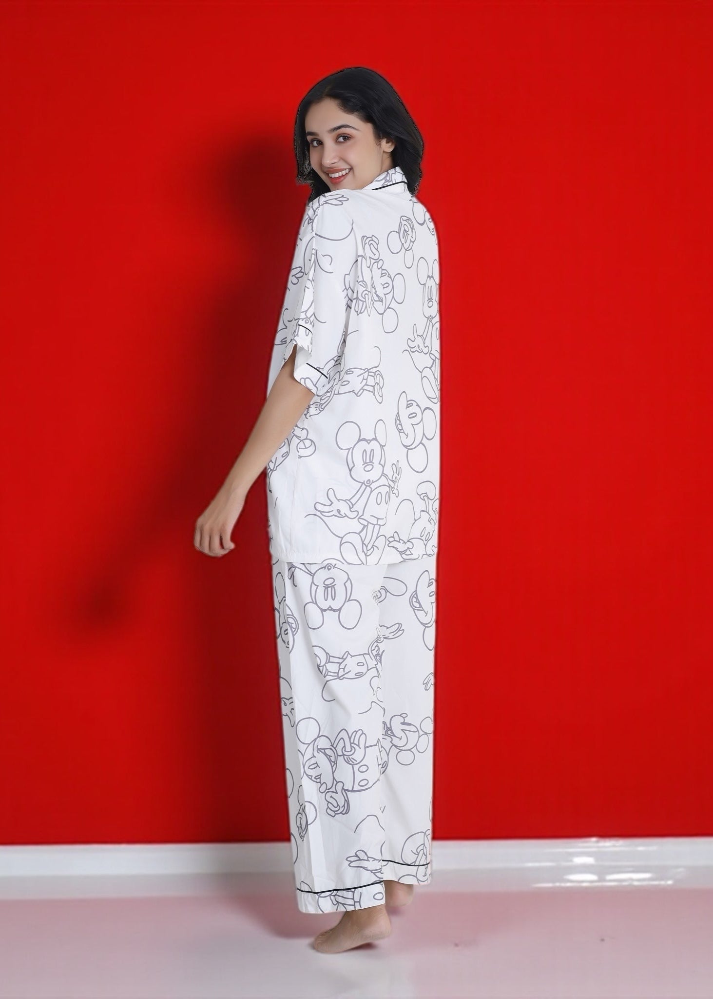 Woman wearing white crepe pyjama set with oversized Mickey Mouse cartoon print, relaxed Disney loungewear by WakeUp Chicq.