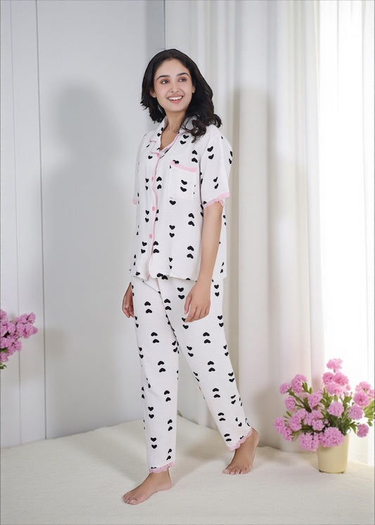 Woman wearing white crushed crepe pyjama set with black heart print and pink lace, by WakeUp Chicq.